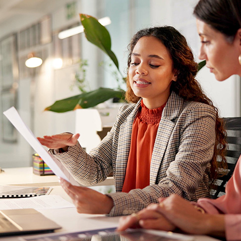two women discussing project details with documents in a modern office setting focusing on collaboration 7 strategies for success