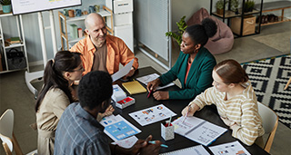 diverse group collaborating in a meeting discussing strategies with documents and notes on a table in a modern workspace focused on teamwork and ideas 4 participants