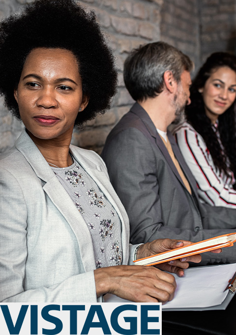 woman with curly hair looking sideways while holding a notebook in a meeting with others fostering leadership skills and strategies for success 9 qualities 9 strategies for growth 9 principles
